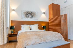 a bedroom with a large bed with a wooden headboard at Guest House - Palácio Diana in Évora