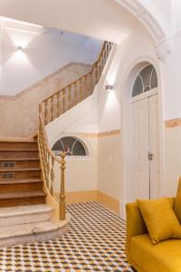 a living room with a staircase and a yellow couch at Guest House - Palácio Diana in Évora