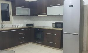 eine Küche mit Holzschränken und einem Kühlschrank aus Edelstahl in der Unterkunft BLUE LUXURY APARTMENT (BREAKBOOKING CY-SERVICES LTD) in Limassol