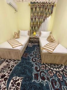 two beds in a room with a carpet at Гостевой дом "BAXSHILLO" in Bukhara