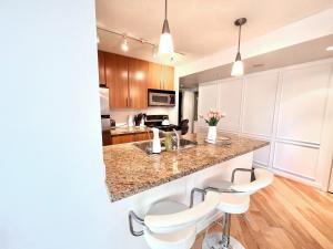 a kitchen with white chairs and a counter in a room at Lovely one-bedroom apartment with swiming pool, hot-tube and gym in central location in Vancouver