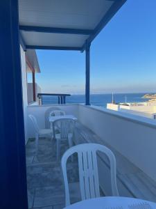a balcony with chairs and tables and the ocean at Sea views - Marble Palace - 2 floors in Tinos Town
