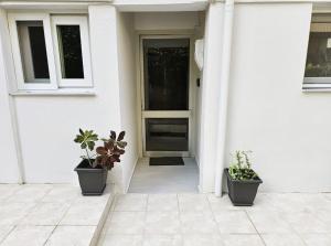 uma casa branca com três vasos de plantas na frente de uma porta em Traveller's Nest Apartment close to center,port,airport em Heraclião