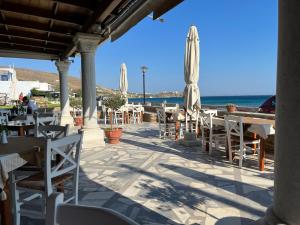 a patio with tables and umbrellas on the beach at Sea views - Marble Palace - 2 floors in Tinos Town