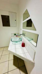 SJO Oasis Hostel في سان خوسيه: منضدة بيضاء مع حوض ومرآة