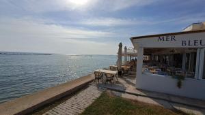 a bar with tables and chairs next to the water at Seaside 2BR Apartment 30m from Sea & Free Parking in Oroklini