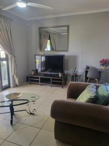 a living room with a couch and a television at Tranquility in Bloemfontein