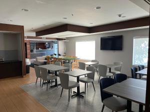 a dining room with tables and chairs and a tv at Baton Rouge Inn & Suites LSU-Medical Corridor in Baton Rouge