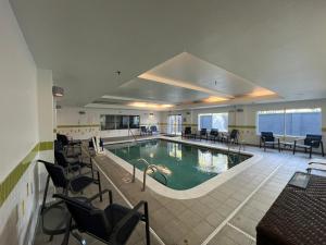 a pool in a hotel with chairs and tables at Baton Rouge Inn & Suites LSU-Medical Corridor in Baton Rouge