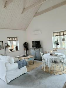 uma sala de estar com um sofá branco e uma mesa em Mysigt hus i liten by nära havet em Ystad