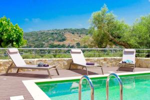 a swimming pool with two lounge chairs next to a swimming pool at Luxury Villa Murtal with private pool in Gerani