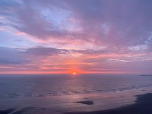 a sunset over the ocean with the sun in the distance at Gorgeous Gower Chalet in Swansea