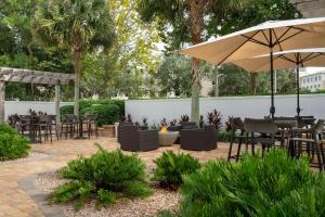 eine Terrasse mit Tischen, Stühlen und einem Sonnenschirm in der Unterkunft Courtyard Jacksonville Flagler Center in Jacksonville
