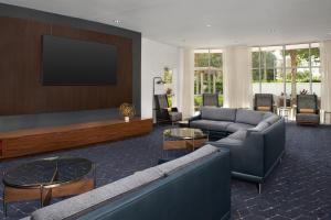 a living room with a couch and a flat screen tv at Courtyard Jacksonville Flagler Center in Jacksonville