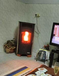 a fireplace with a fire in it next to a table at CASA DA VOVÓ CÉU - Casa de Campo Gandaresa - Country House, entre COIMBRA e AVEIRO, a 15 minutos carro Praia Mira - Quintal com piscina desmontável in Cantanhede