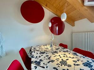 a dining room with a table and red chairs at Trilo Riflessi d'Alpe in Lavarone