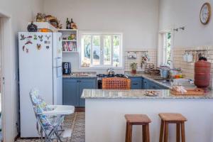 eine Küche mit blauen Schränken und einem weißen Kühlschrank in der Unterkunft Casa Amorada-Vista Linda, Conforto e Paz in Campos do Jordão
