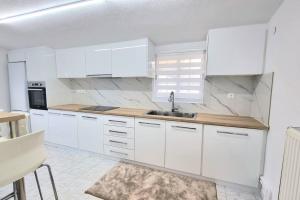 a white kitchen with white cabinets and a sink at Little village Trikala 