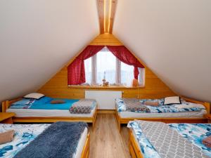 um quarto no sótão com 3 camas e uma janela em Gazdówka na Mosornym Groniu em Zawoja