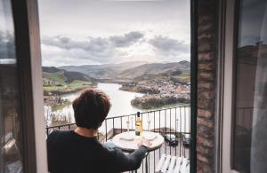 a man sitting at a table looking out a window at a river at Lake House in Sassocorvaro