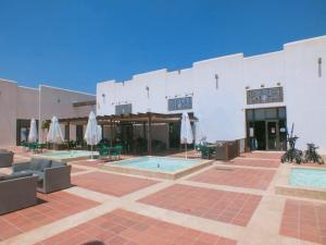 un edificio con 2 piscinas y sombrillas en Las Terrazas de la Torre Golf Murcia, en Murcia