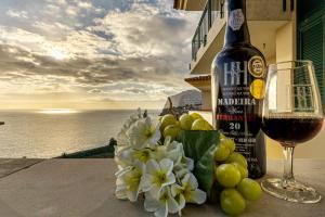 a bottle of wine and a bowl of grapes and a glass of wine at Ocean view and Infinity pool Apartment in Funchal