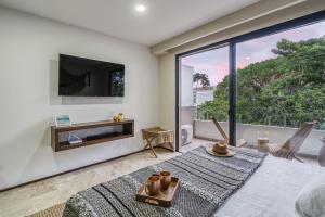 a living room with a large window and a tv at Fast-Wifi Sunset Studio Tulum with Rooftop and Pool SPA in Tulum