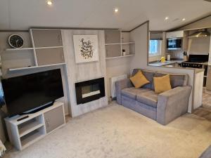 a living room with a couch and a television at Bird Lake Pastures Holiday Caravan in Northampton