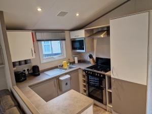 a small kitchen with a sink and a stove at Bird Lake Pastures Holiday Caravan in Northampton