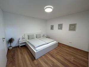 a white bedroom with a bed and a wooden floor at Ferienwohnung Gmunden City in Gmunden