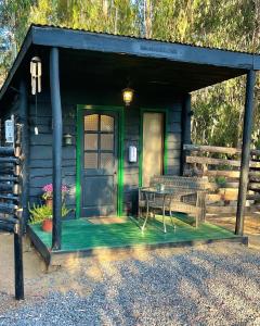 Cabaña con puerta verde y mesa en El Bosque Lodge en Algarrobo