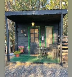 a cabin with a table and a green door at El Bosque Lodge in Algarrobo