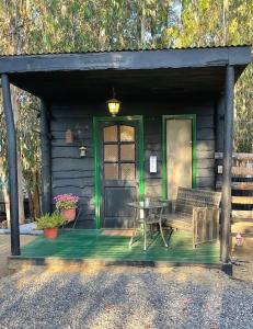 Cabaña con mesa y puerta verde en El Bosque Lodge en Algarrobo