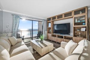 a living room with a couch and a tv at Oceanfront 2 Bedroom Modern Beach Condo w Pool in Ocean City