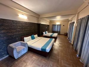 a hotel room with two beds and a chair at Misty Dam Wayanad Premium Resort With Banasura Dam View in Padinjarathara