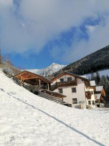 a building on a snow covered slope with mountains in the background at Wiesenheimhof - Apt 1 in Terento