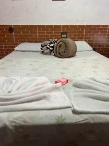 a bed with white sheets and a hat on it at Pesque pague pousada do Carlinho in Pinheiral