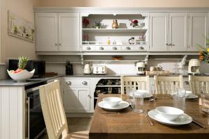eine Küche mit weißen Schränken und einem Holztisch in der Unterkunft Downwood Vineyard Manor in Idyllic Countryside in Blandford Forum