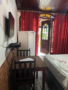 a room with a table and a kitchen with a refrigerator at Pesque pague pousada do Carlinho in Pinheiral