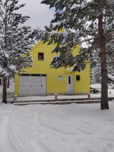 a yellow house with two garage doors in the snow at Vikendica Pinus Blidinje in Blidinje