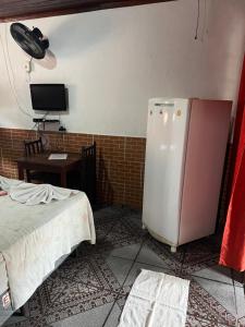 a room with a refrigerator and a table and a desk at Pesque pague pousada do Carlinho in Pinheiral