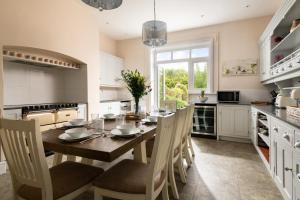 een keuken met een houten tafel met stoelen en een eetkamer bij Downwood Vineyard Manor in Idyllic Countryside in Blandford Forum