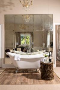 ein Badezimmer mit Badewanne und großem Spiegel in der Unterkunft Downwood Vineyard Manor in Idyllic Countryside in Blandford Forum + 105 Fotos