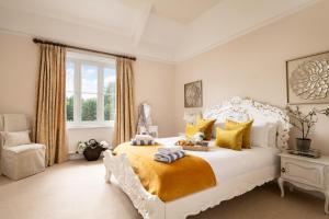 ein Schlafzimmer mit einem großen weißen Bett und einem Stuhl in der Unterkunft Downwood Vineyard Manor in Idyllic Countryside in Blandford Forum