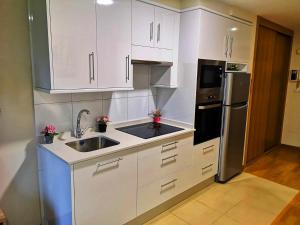 a kitchen with white cabinets and a sink and a refrigerator at Apartamento A Cabana II in Porriño