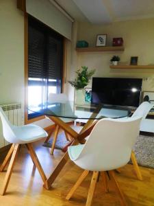 a dining room with a glass table and two white chairs at Apartamento A Cabana II in Porriño