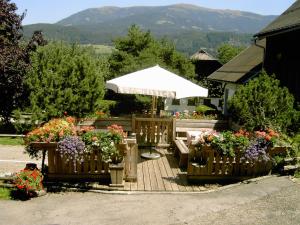 eine Holzterrasse mit Blumen und einem Sonnenschirm in der Unterkunft Gasthof Tell in Paternion