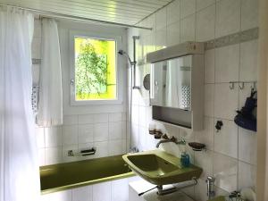 ein Bad mit einem grünen Waschbecken und einem Fenster in der Unterkunft Elfe-Apartments FerienMietWohnungen in Emmetten