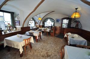 un ristorante con tavoli e sedie bianchi e finestre di Gasthof Tell a Paternion