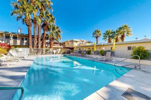 a swimming pool with palm trees in a resort at Hermosa Hideaway Permit #39494 in Palm Springs